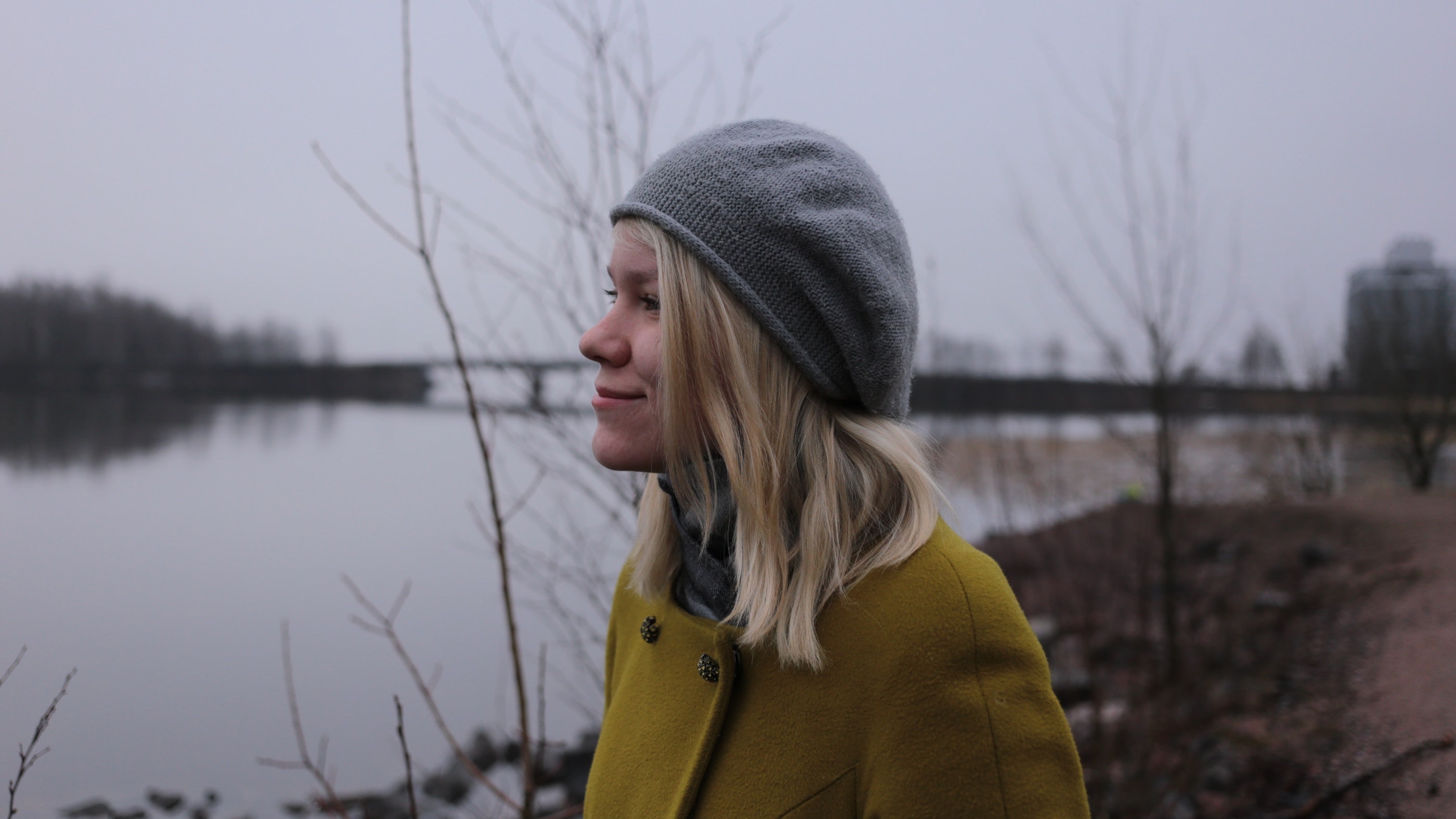 Bilde av ung dame med elv og bro i bakgrunnen. Foto av Luiza Sayfullina fra https://unsplash.com/@muzaluiza